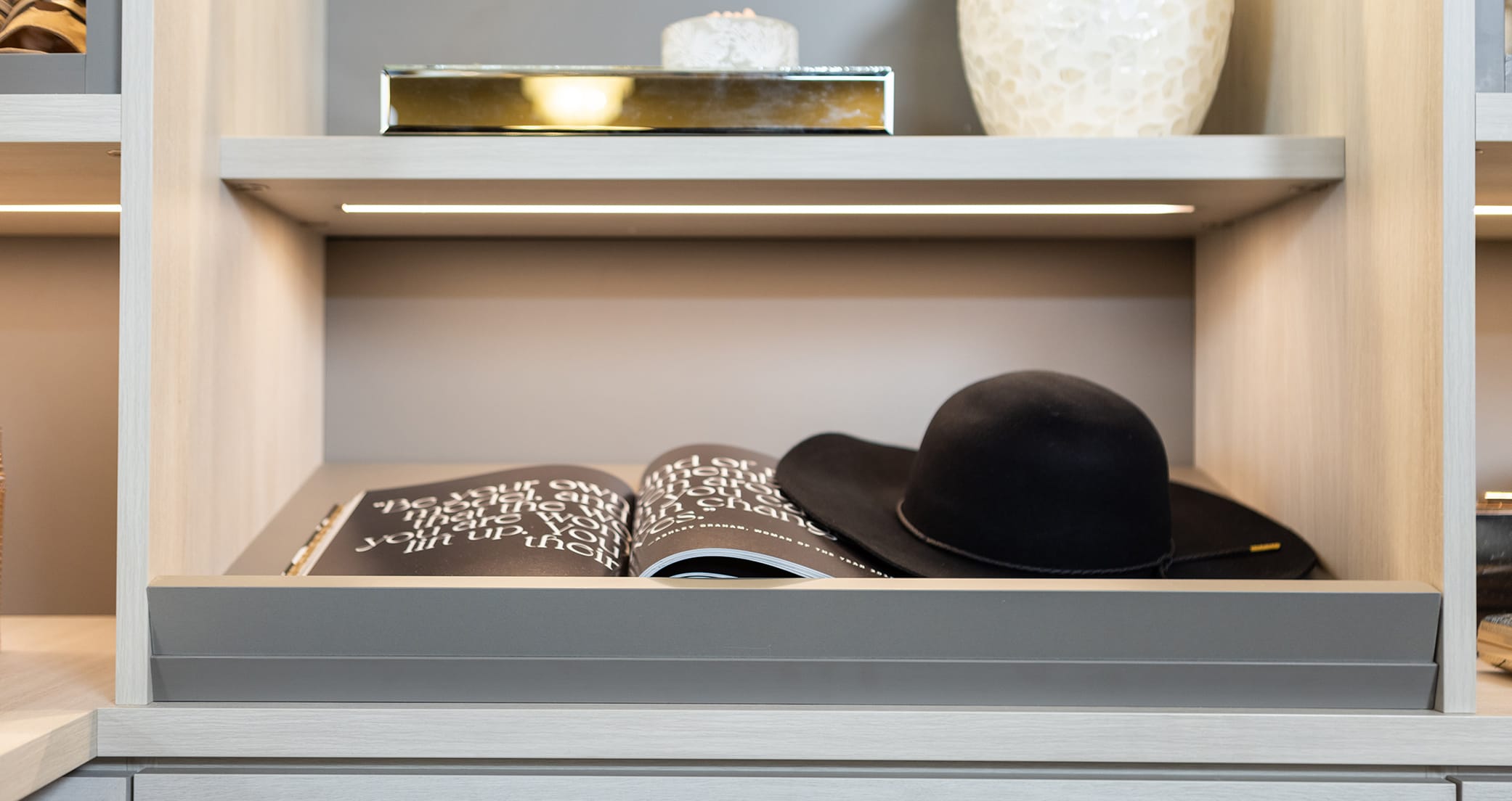 Open shelving in walk in closet with ribbon led lighting by California Closets