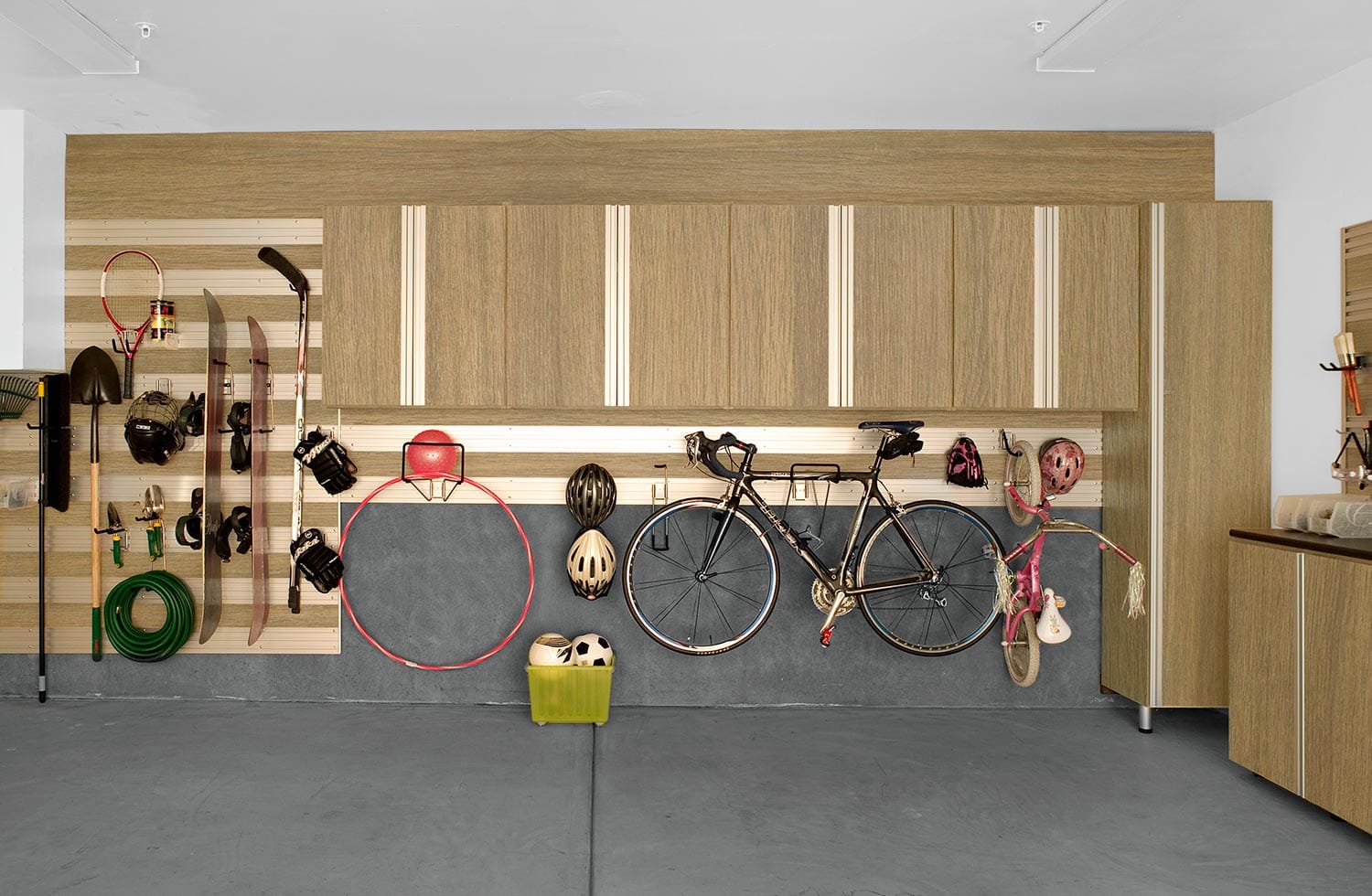 Custom garage storage systems with wall track and cabinets by California Closets