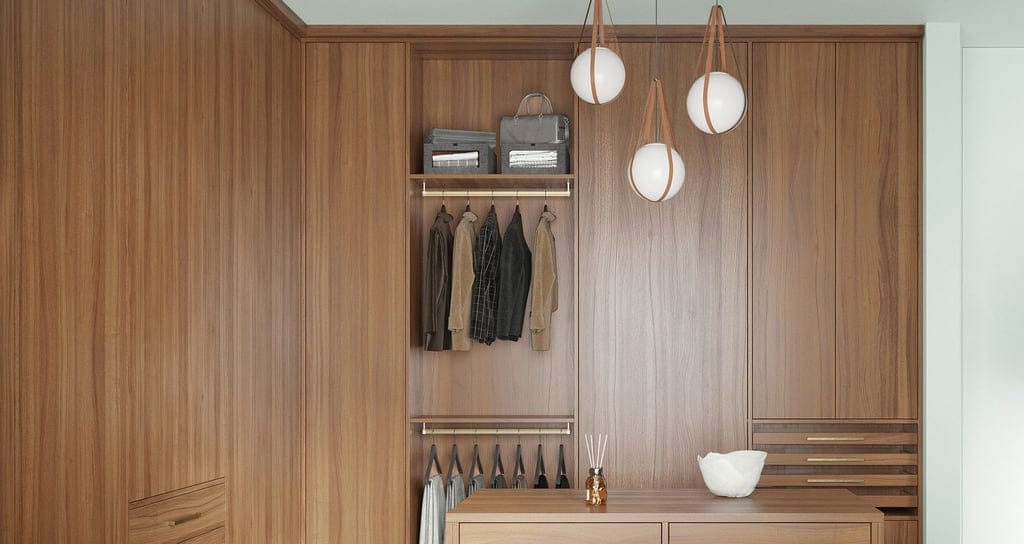 A modern, minimalist walk in closet in natural wood grain finish with floor to ceiling cabinets and center island created by California Closets